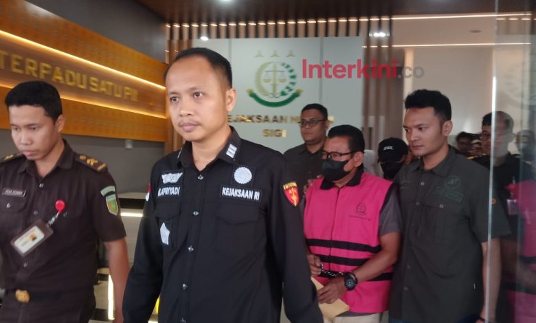 Tersangka kasus dugaan gratifikasi proyek olahan pakan di Kabupaten Sigi digiring petugas keluar dari Kantor Kejaksaan Negeri Sigi usai penetapan tersangka, Selasa (19/5/2026). Penyidik mengungkap dugaan fee proyek dipatok 10–20 persen dari nilai pekerjaan.