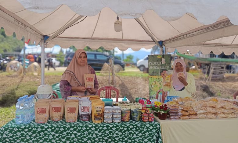 Pelaku UMKM binaan Pemerintah Kabupaten Sigi menjaga stan produk lokal pada Festival Danau Lindu (FDL) 2026 di kawasan Danau Lindu, Kabupaten Sigi. Sejumlah pelaku usaha menilai festival membantu memperluas pemasaran produk, namun berharap kualitas jaringan telekomunikasi ditingkatkan untuk mendukung transaksi digital pada penyelenggaraan berikutnya. Foto: Interkini.co